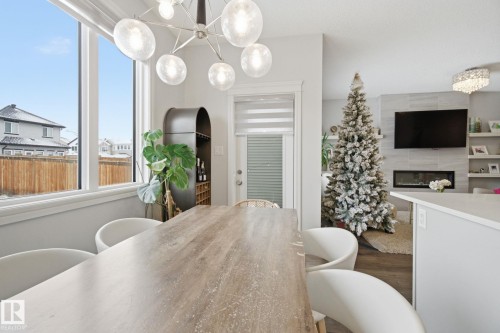 Dining space with hanging lights, dark wood finished floors, and a tile fireplace - 9942 222A St Nw, Edmonton, AB - Indoor