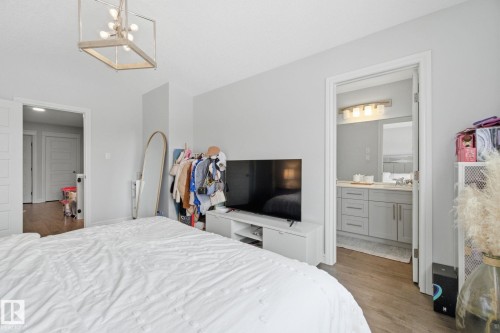 Bedroom featuring wood finished floors, lofted ceiling, hanging lights, and ensuite bath - 9942 222A St Nw, Edmonton, AB - Indoor Photo Showing Bedroom