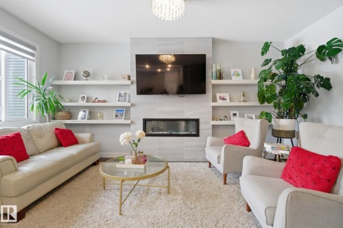 Living room featuring suspended lighting and a tiled fireplace - 9942 222A St Nw, Edmonton, AB - Indoor Photo Showing Living Room With Fireplace