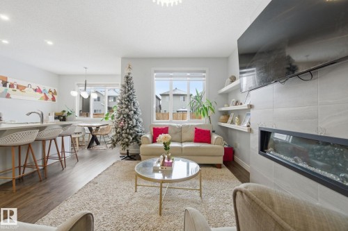 Living area featuring wood finished floors, a chandelier, and a fireplace - 9942 222A St Nw, Edmonton, AB - Indoor Photo Showing Living Room With Fireplace