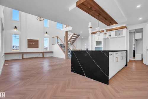 Kitchen featuring white cabinets, parquet floors, open floor plan, hanging light fixtures, and a high ceiling - 463 Crystal Creek Link, Leduc, AB - Indoor
