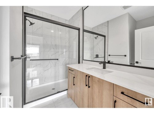 Bathroom featuring vanity, a marble finish shower, and light marble finish flooring - 426 Crystal Creek Link, Leduc, AB - Indoor Photo Showing Bathroom