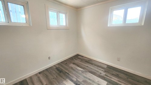 Empty room with dark wood-style flooring, plenty of natural light, and ornamental molding - 12139 81 Street, Edmonton, AB - Indoor Photo Showing Other Room