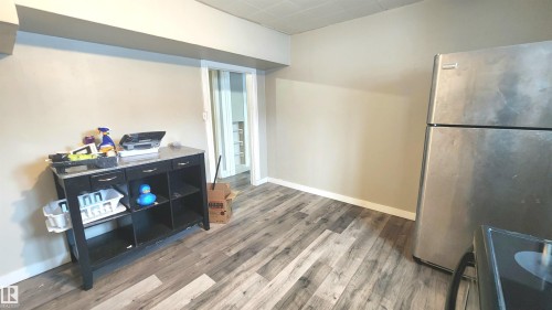 Kitchen with freestanding refrigerator, black range with electric cooktop, wood finished floors, and dark cabinets - 12139 81 Street, Edmonton, AB - Indoor Photo Showing Other Room