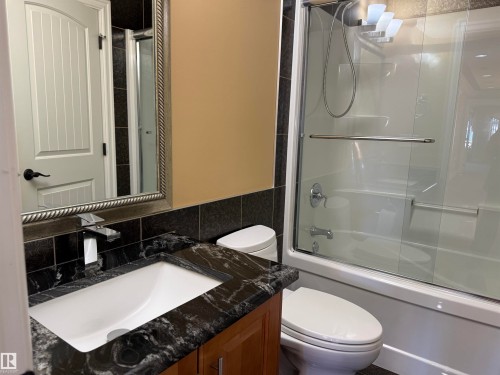 Full bath featuring vanity, bath / shower combo with glass door, and tile walls - 816 Wildwood Crescent Nw, Edmonton, AB - Indoor Photo Showing Bathroom