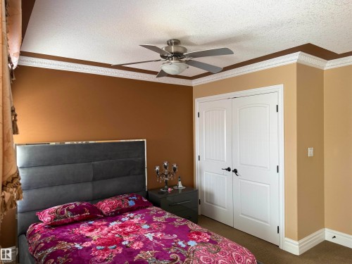 Bedroom featuring crown molding, ceiling fan, dark colored carpet, a textured ceiling, and a closet - 816 Wildwood Crescent Nw, Edmonton, AB - Indoor Photo Showing Bedroom
