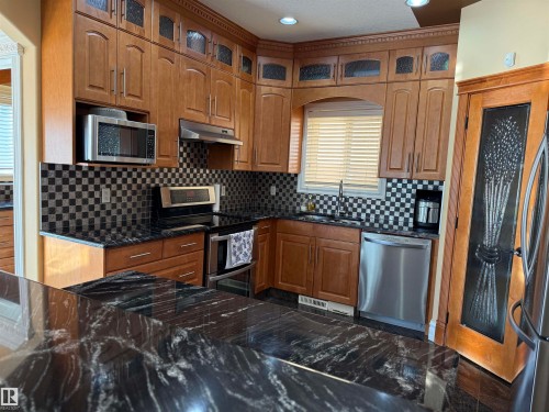 Kitchen with glass insert cabinets, stainless steel appliances, wood finish cabinets, dark stone countertops, and recessed lighting - 816 Wildwood Crescent Nw, Edmonton, AB - Indoor Photo Showing Kitchen With Stainless Steel Kitchen