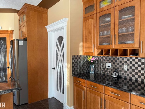 Kitchen with glass insert cabinets, wood finish cabinetry, freestanding refrigerator, and dark stone countertops - 816 Wildwood Crescent Nw, Edmonton, AB - Indoor Photo Showing Kitchen