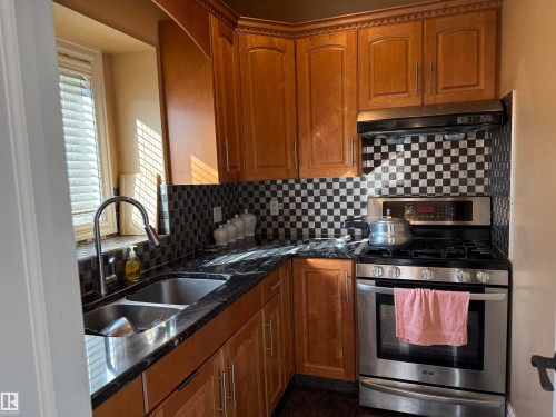 Kitchen with gas range, dark stone counters, wood finish cabinetry, tasteful backsplash, and healthy amount of natural light - 816 Wildwood Crescent Nw, Edmonton, AB - Indoor Photo Showing Kitchen With Stainless Steel Kitchen With Double Sink