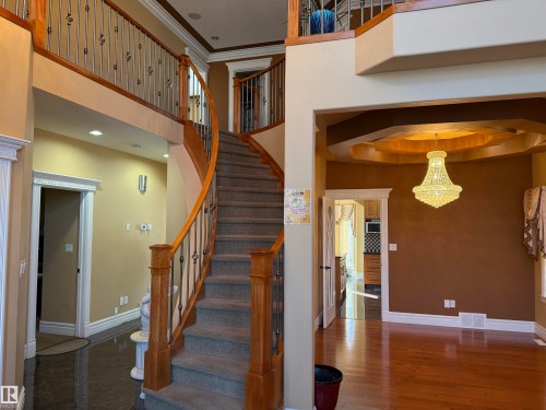 Stairs with ornamental molding, a high ceiling, a chandelier, and wood finished floors - 816 Wildwood Crescent Nw, Edmonton, AB - Indoor Photo Showing Other Room