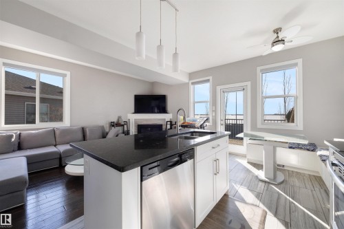 Kitchen featuring open floor plan, white cabinets, stainless steel appliances, and hanging light fixtures - 81 Richmond Link, Fort Saskatchewan, AB - Indoor Photo Showing Kitchen With Double Sink