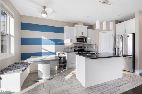 Kitchen featuring stainless steel appliances, white cabinetry, ceiling fan, and dark stone countertops - 81 Richmond Link, Fort Saskatchewan, AB - Indoor Photo Showing Kitchen With Stainless Steel Kitchen With Upgraded Kitchen