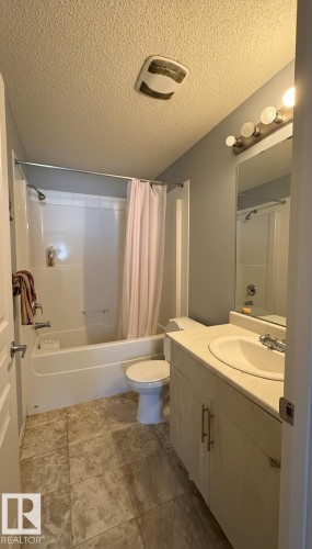 Bathroom with vanity, shower / tub combo, and a textured ceiling - 133 301 Clareview Station Drive, Edmonton, AB - Indoor Photo Showing Bathroom