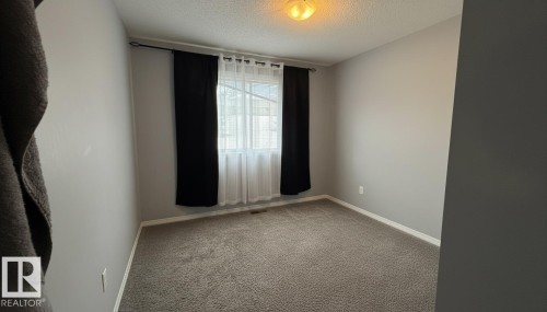 Carpeted spare room with a textured ceiling and baseboards - 133 301 Clareview Station Drive, Edmonton, AB - Indoor Photo Showing Other Room