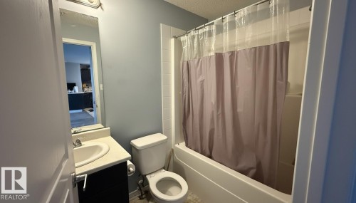 Full bathroom featuring vanity, shower / bathtub combination with curtain, and a textured ceiling - 133 301 Clareview Station Drive, Edmonton, AB - Indoor Photo Showing Bathroom