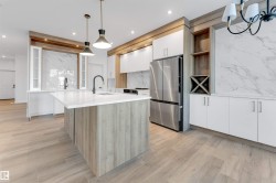 Kitchen featuring white cabinets, hanging light fixtures, freestanding refrigerator, modern cabinets, and light wood-style flooring - 