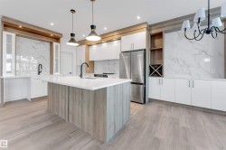 Kitchen featuring white cabinetry, modern cabinets, freestanding refrigerator, decorative light fixtures, and a chandelier - 