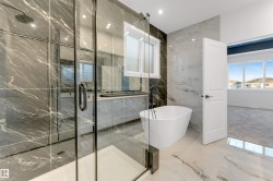 Bathroom with a freestanding bath, marble tiled floors, a marble finish shower, stone wall, and recessed lighting - 