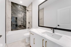Bathroom with light marble finish flooring, a combined bath / shower with marble appearance, and vanity - 