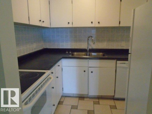 Kitchen with white appliances, white cabinetry, light flooring, dark countertops, and backsplash - 3041 Tudor Glen, St. Albert, AB 