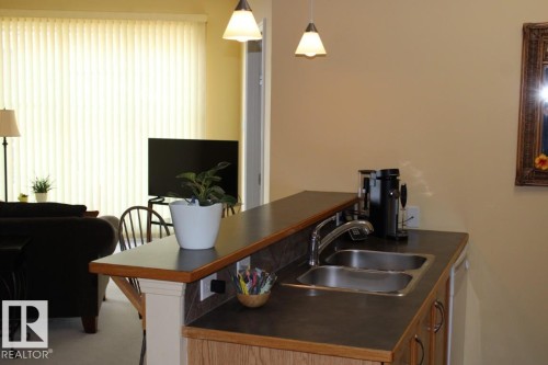 Kitchen featuring dark countertops, hanging light fixtures, and dishwasher - 330 4831 104A Street, Edmonton, AB - Indoor Photo Showing Kitchen With Double Sink