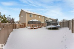 Snow covered rear of property with a gazebo, a trampoline, a fenced backyard, a wooden deck, and a gate - 