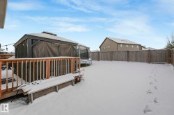 Yard covered in snow featuring a trampoline, a fenced backyard, a wooden deck, and a gazebo - 