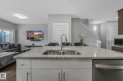 Kitchen with open floor plan, stainless steel appliances, light stone countertops, and a kitchen island with sink - 