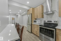 Kitchen with appliances with stainless steel finishes, wall chimney range hood, tasteful backsplash, light wood-type flooring, and recessed lighting - 
