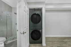 Laundry room featuring stacked washer and clothes dryer and wood finished floors - 