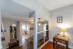 Corridor featuring an upstairs landing and dark wood-style flooring - 
