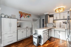 Kitchen with white cabinets, a peninsula, stainless steel appliances, and dark wood-style floors - 