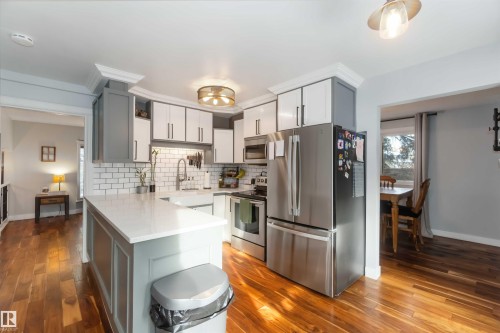 Kitchen featuring stainless steel appliances, dark wood-type flooring, a peninsula, and tasteful backsplash - 6 Garraway Pl, St. Albert, AB - Indoor Photo Showing Kitchen With Upgraded Kitchen