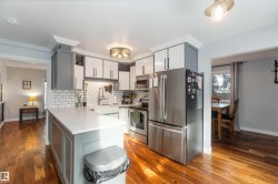 Kitchen featuring stainless steel appliances, dark wood-type flooring, a peninsula, and tasteful backsplash - 