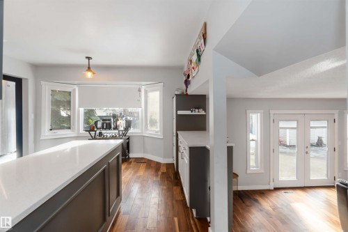 Kitchen with french doors, dark wood-style flooring, and light stone countertops - 6 Garraway Pl, St. Albert, AB - Indoor