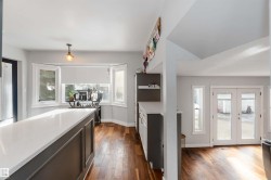 Kitchen with french doors, dark wood-style flooring, and light stone countertops - 