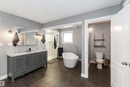 Bathroom with double vanity, a stall shower, a freestanding bath, and dark tile patterned floors - 6 Garraway Pl, St. Albert, AB - Indoor Photo Showing Bathroom