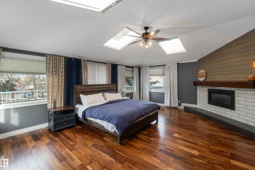 Bedroom with wood-type flooring, a fireplace, and a ceiling fan - 6 Garraway Pl, St. Albert, AB - Indoor Photo Showing Bedroom