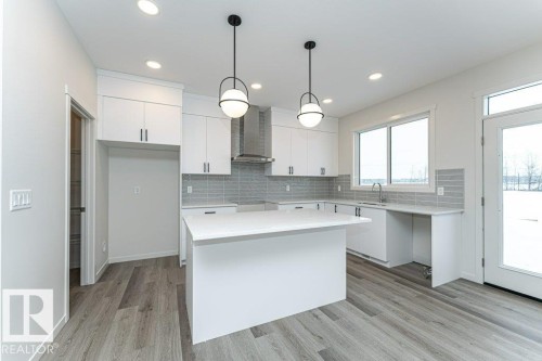 Kitchen featuring decorative backsplash, light wood-style flooring, and white cabinetry - 3972 Wren Loop, Edmonton, AB - Indoor Photo Showing Kitchen With Upgraded Kitchen