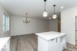 Kitchen with white cabinetry, light wood-type flooring, light stone counters, and a kitchen island - 