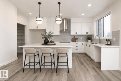 The kitchen features white cabinetry, a large center island, and wood-look flooring - 