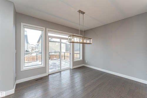 Unfurnished dining area with dark wood finished floors and hanging lights - 3611 Keswick Boulevard, Edmonton, AB - Indoor Photo Showing Other Room