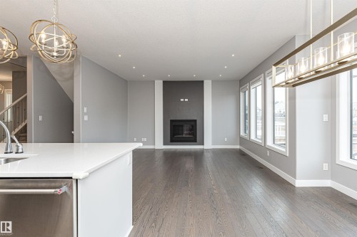 Unfurnished living room with suspended lighting, dark wood finished floors, and a fireplace - 3611 Keswick Boulevard, Edmonton, AB - Indoor With Fireplace