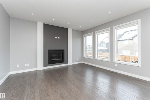 Unfurnished living room with a glass covered fireplace, wood finished floors, and recessed lighting - 3611 Keswick Boulevard, Edmonton, AB - Indoor Photo Showing Living Room With Fireplace