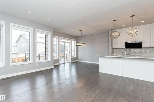 Kitchen with white cabinets, decorative backsplash, dark wood-type flooring, exhaust hood, and open floor plan - 3611 Keswick Boulevard, Edmonton, AB - Indoor Photo Showing Kitchen