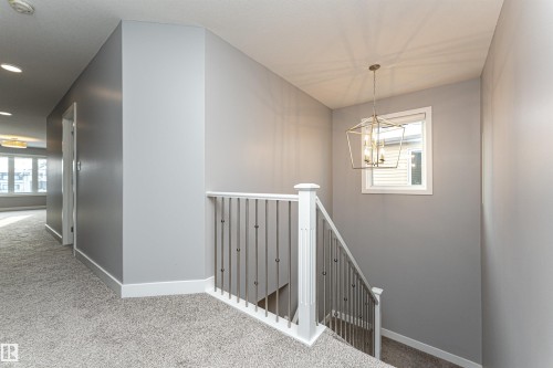 Hallway with carpet, hanging lights, and an upstairs landing - 3611 Keswick Boulevard, Edmonton, AB - Indoor Photo Showing Other Room