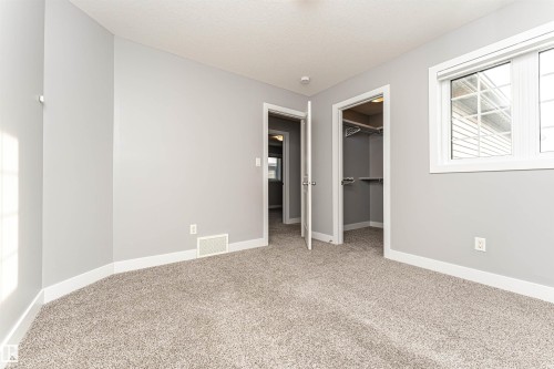 Unfurnished bedroom with a spacious closet, carpet, and a textured ceiling - 3611 Keswick Boulevard, Edmonton, AB - Indoor Photo Showing Other Room