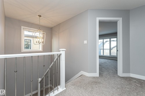 Hall with light colored carpet and suspended lighting - 3611 Keswick Boulevard, Edmonton, AB - Indoor Photo Showing Other Room
