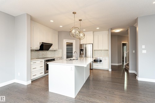 Kitchen with white cabinetry, a kitchen island with sink, suspended lighting, and stainless steel appliances - 3611 Keswick Boulevard, Edmonton, AB - Indoor Photo Showing Kitchen With Upgraded Kitchen