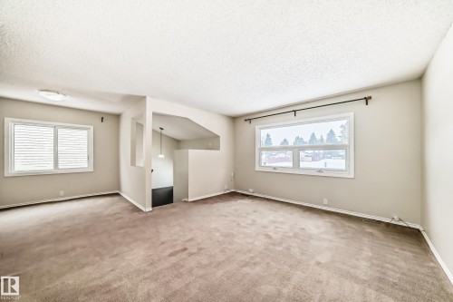 Unfurnished living room with light colored carpet and a textured ceiling - 5308 20 Avenue, Edmonton, AB - Indoor Photo Showing Other Room